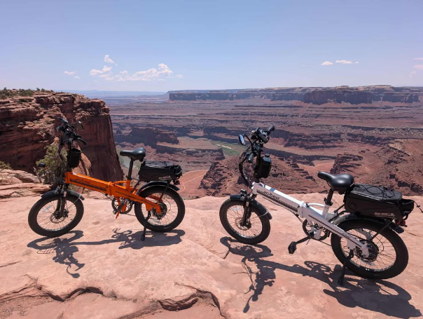 Two e-bikes parked on a cliff overlooking a vast canyon.