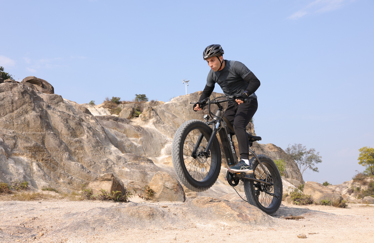 A person riding an e - bike on rocky terrain, demonstrating its climbing ability.