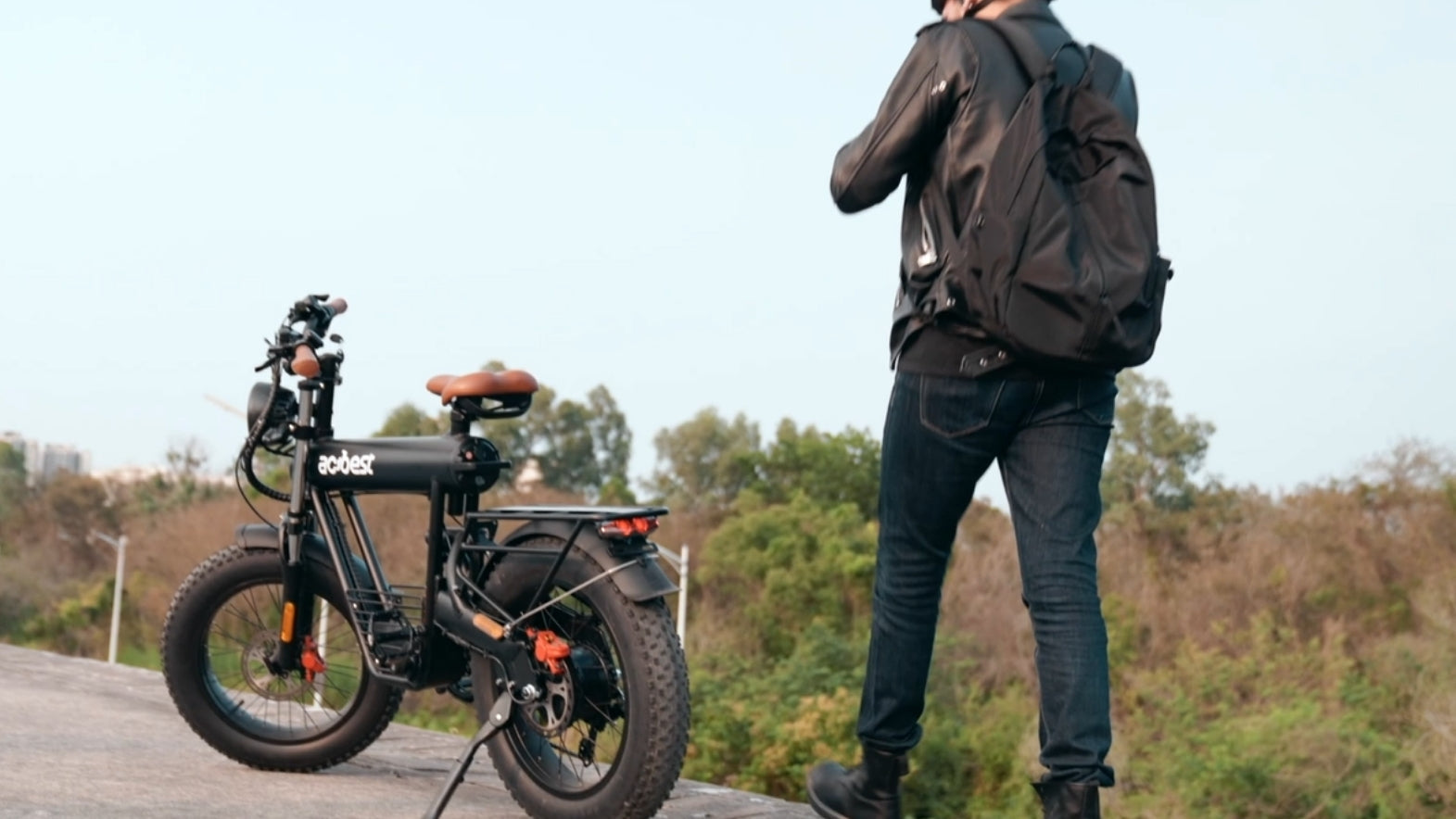 A man with a backpack stands next to an all-terrain electric bike