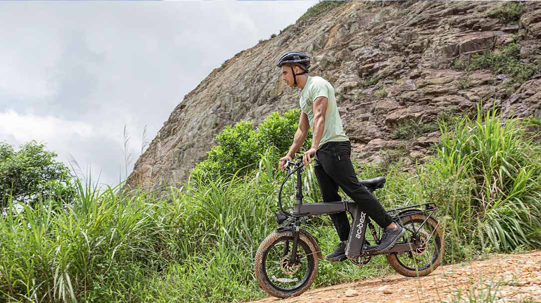 Man riding a black electric bike on a rocky trail, wearing a helmet, outdoor eMTB adventure scene