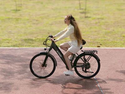 Woman with long hair riding an Actbestbike Core Series e-bike in a park.