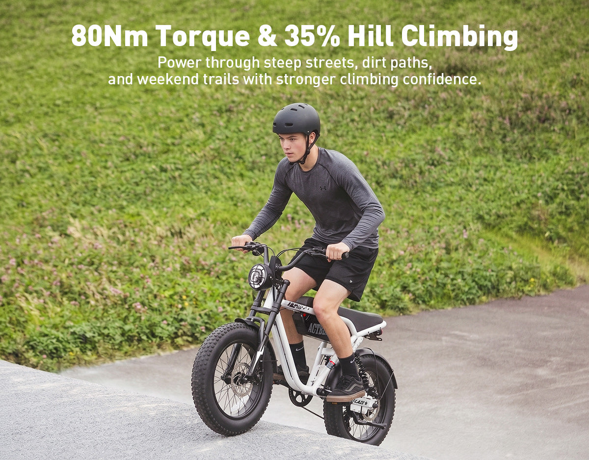 A person riding a small electric bicycle on a paved path with grassy hills in the background. White text at the top reads '80Nm Torque & 35% Hill Climbing' with a supporting sentence about power through steep streets, dirt paths, and weekend trails.