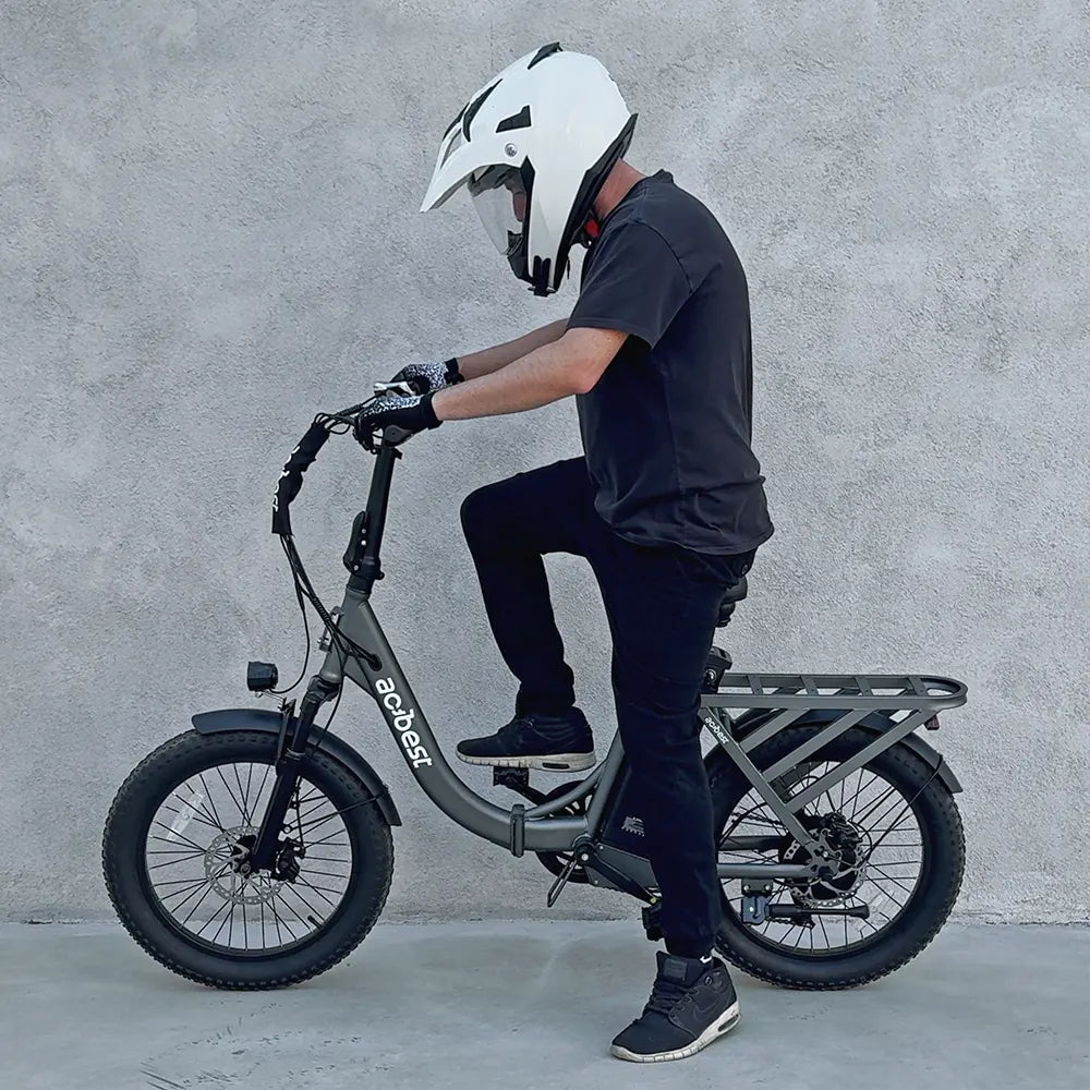 Grey Mars Folding Electric Bike with rider in helmet, showcasing fat tires and rear cargo rack.