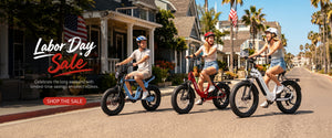 A man and two women riding electric bicycles down a sunny residential street lined with palm trees. The scene includes promotional text reading 'Labor Day Sale' and 'SHOP THE SALE' on the left side of the image.