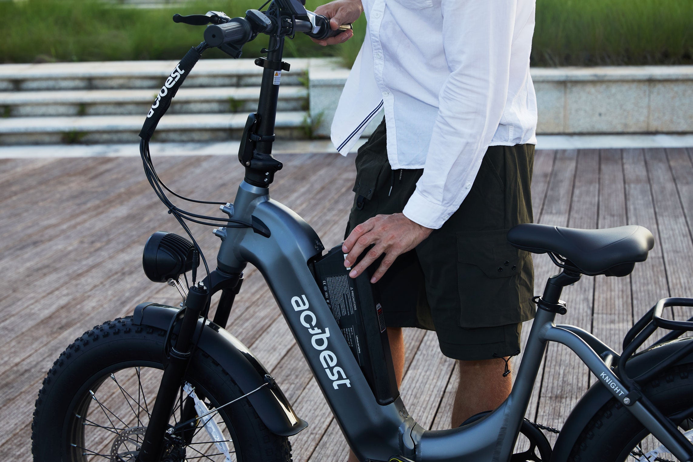 Man removing integrated ebike battery from frame on boardwalk
