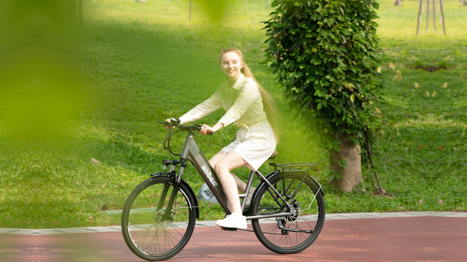 A blonde girl rides a Lightweight Electric Bike on the road in the park