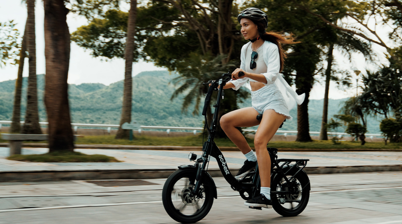 A woman wearing a helmet is riding an electric bicycle in the park for exercise.