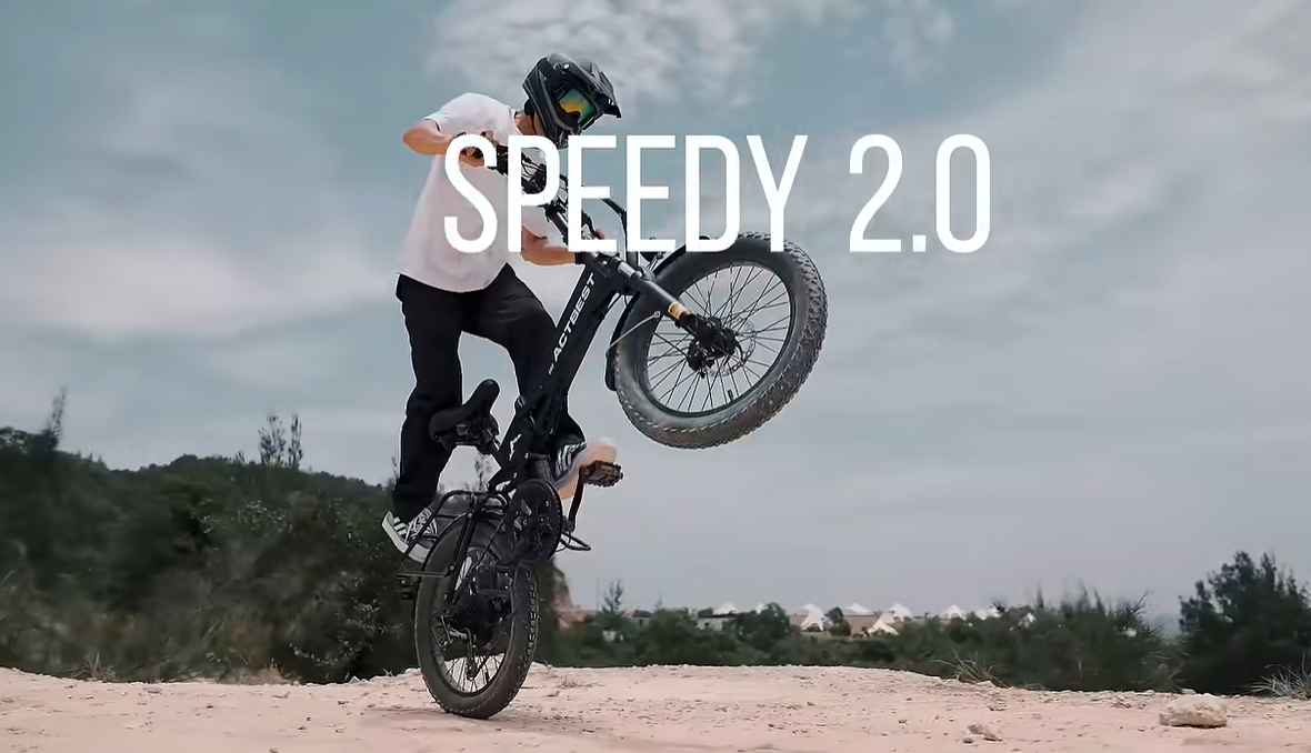 A rider in a helmet performs a wheelie on a black ACTBEST fat-tire electric bike on a dirt trail, with the text "SPEEDY 2.0" overlaid