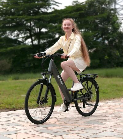 A young woman with long hair smiling as she rides a black Acibest electric bike on a path.