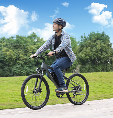 Man riding gray Actbest Race Electric Mountain Bike on smooth path outdoors.