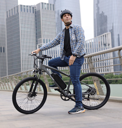Man on gray Actbest electric mountain bike in urban setting with city skyline.