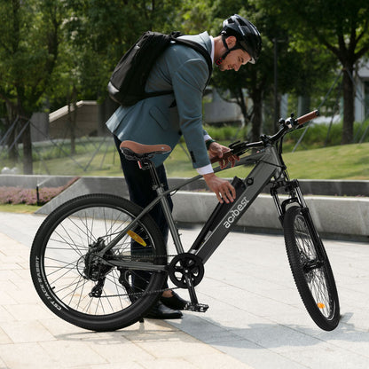 Man in suit adjusting gray Core Mountain Electric Bike on city sidewalk.