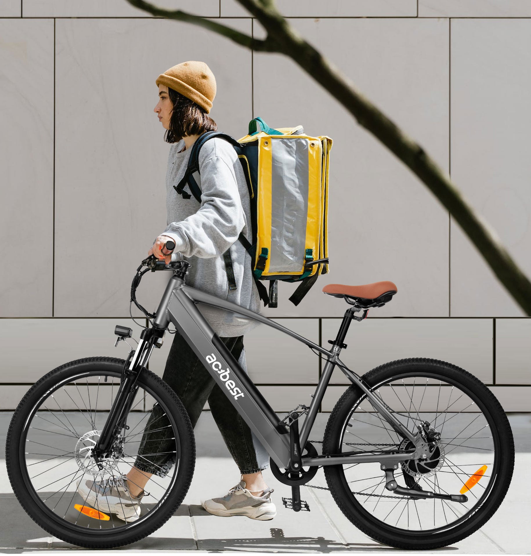 Woman walking with gray Core Mountain Electric Bike and a yellow backpack.