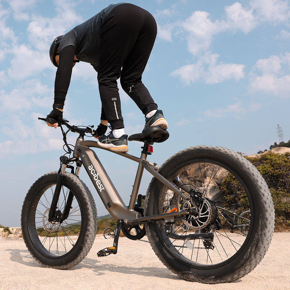 Person performing a stunt on Actbest Ranger electric bike with fat tires on rocky terrain.