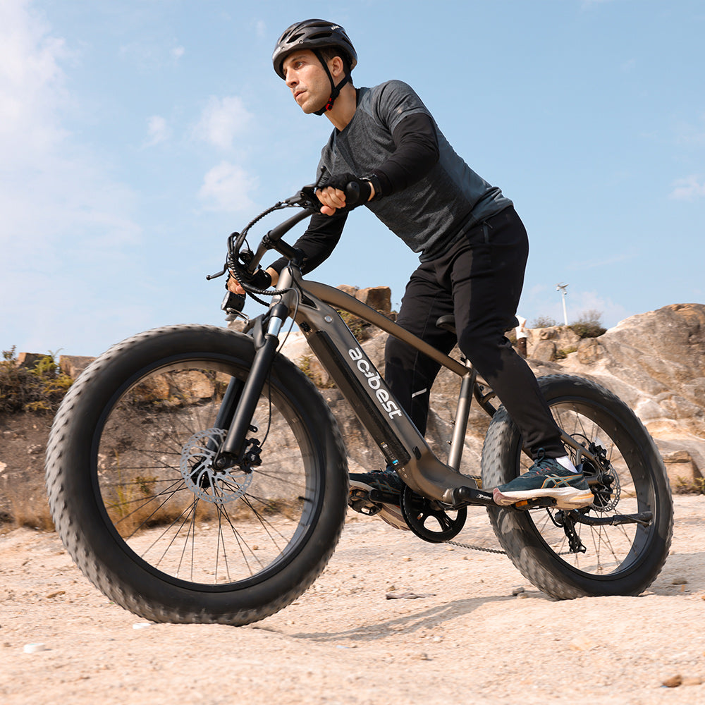 Rider on Actbest Ranger electric bike with fat tires navigating rocky terrain.