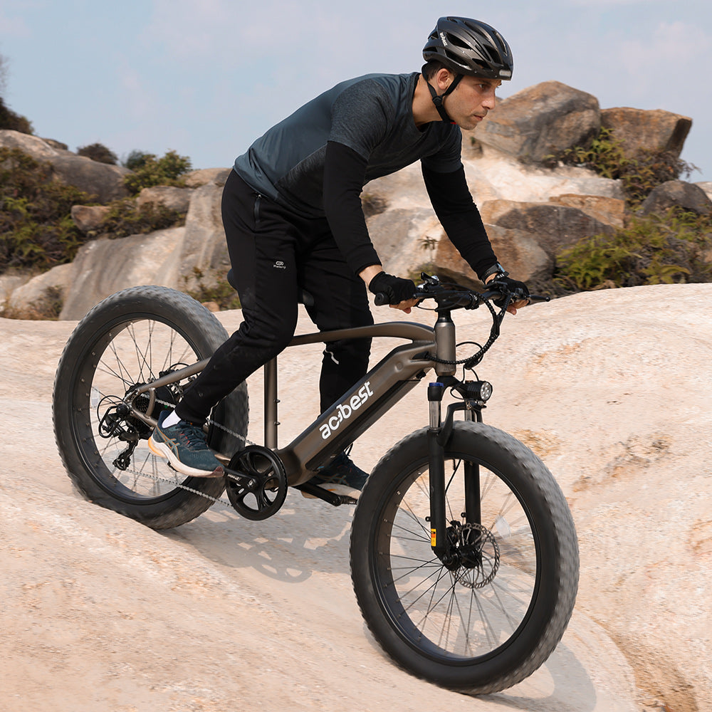 Man riding Actbest Ranger electric bike on rocky terrain with fat tires.