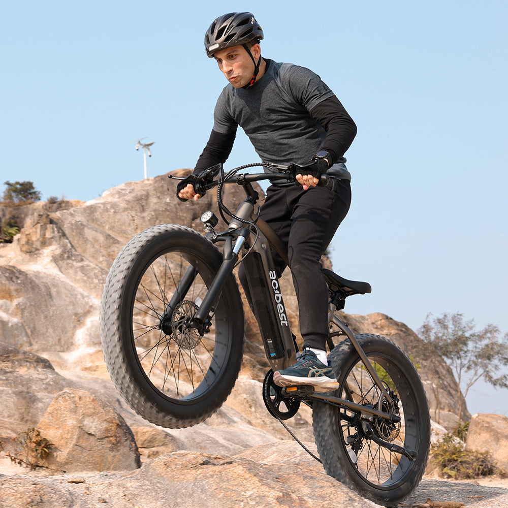 Man jumping on Actbest Ranger fat tire electric bike on rocky terrain.