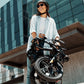 Woman carrying a folded black Actbest electric bike in urban environment.