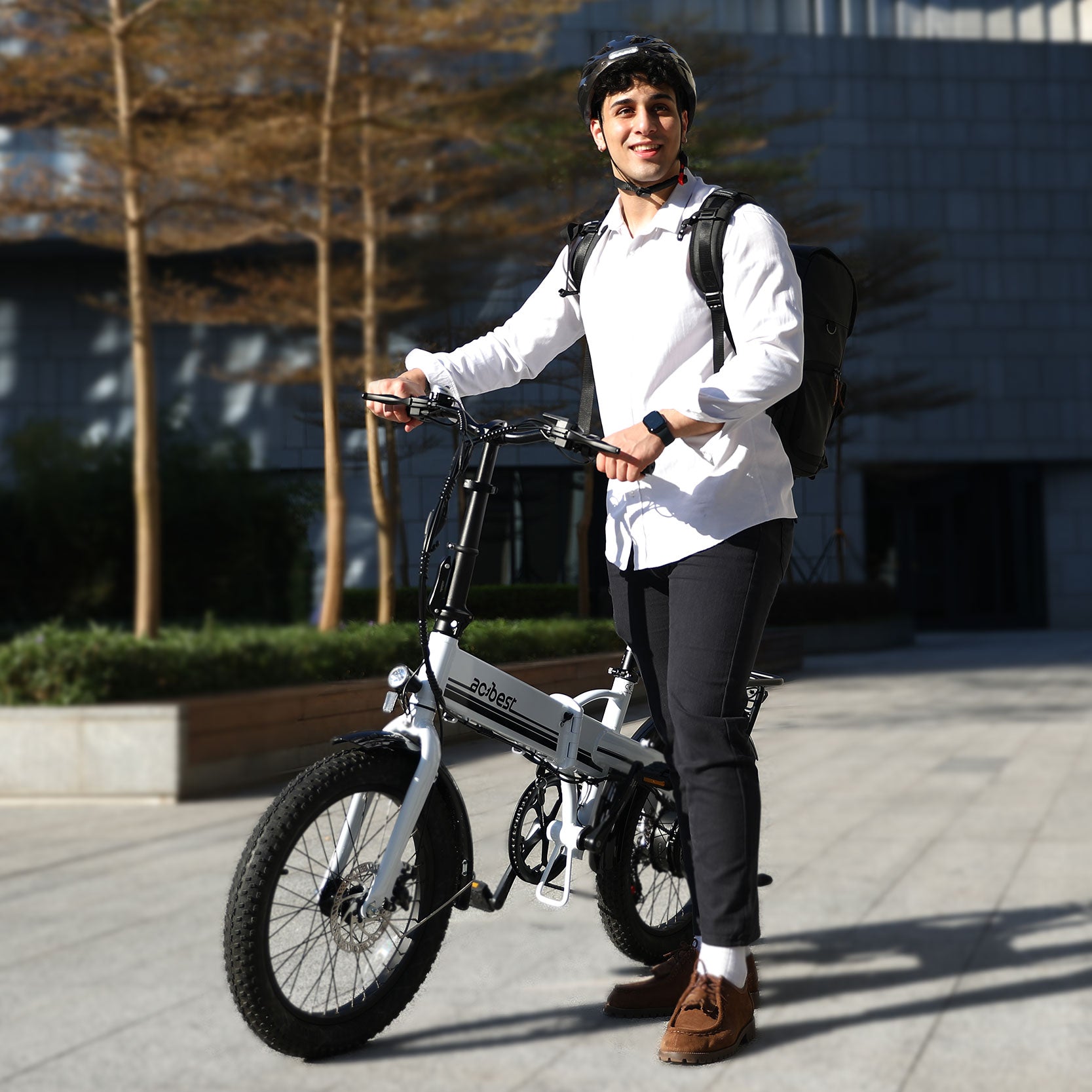 Man on a white foldable electric bike with fat tires, ready for urban rides.
