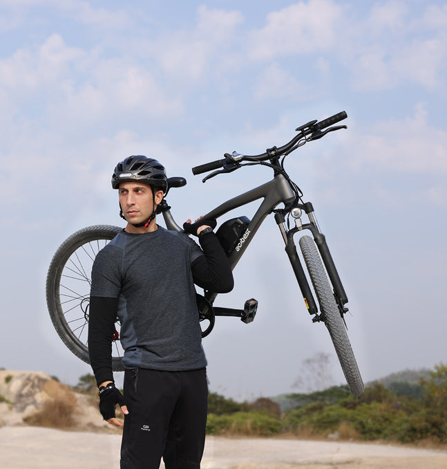 Man carrying gray Actbest Race Electric Mountain Bike over shoulder