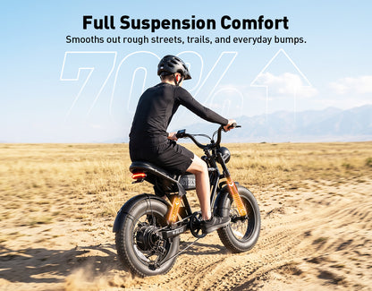 A person riding an electric fat-tire bike on a sandy desert road, wearing a black long-sleeve shirt, shorts, and a helmet. The image includes the text 'Full Suspension Comfort' at the top, with a faint '7061' watermark in the background.