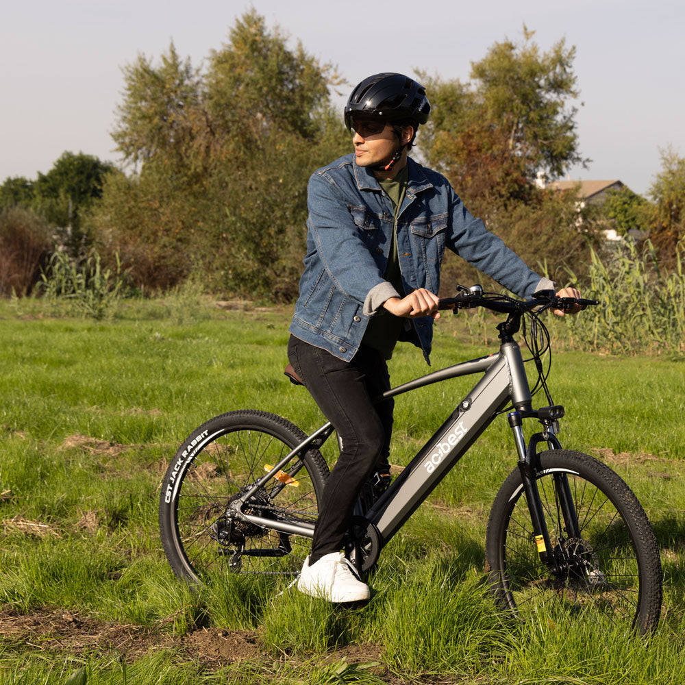 Man on gray Core Mountain Electric Bike in a grassy field.